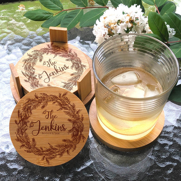 Bamboo coasters with engraved design and a glass of iced tea on a stone surface.
