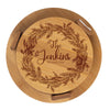Round wooden cutting board with engraved wreath and 'The Jenkins' text on a white background